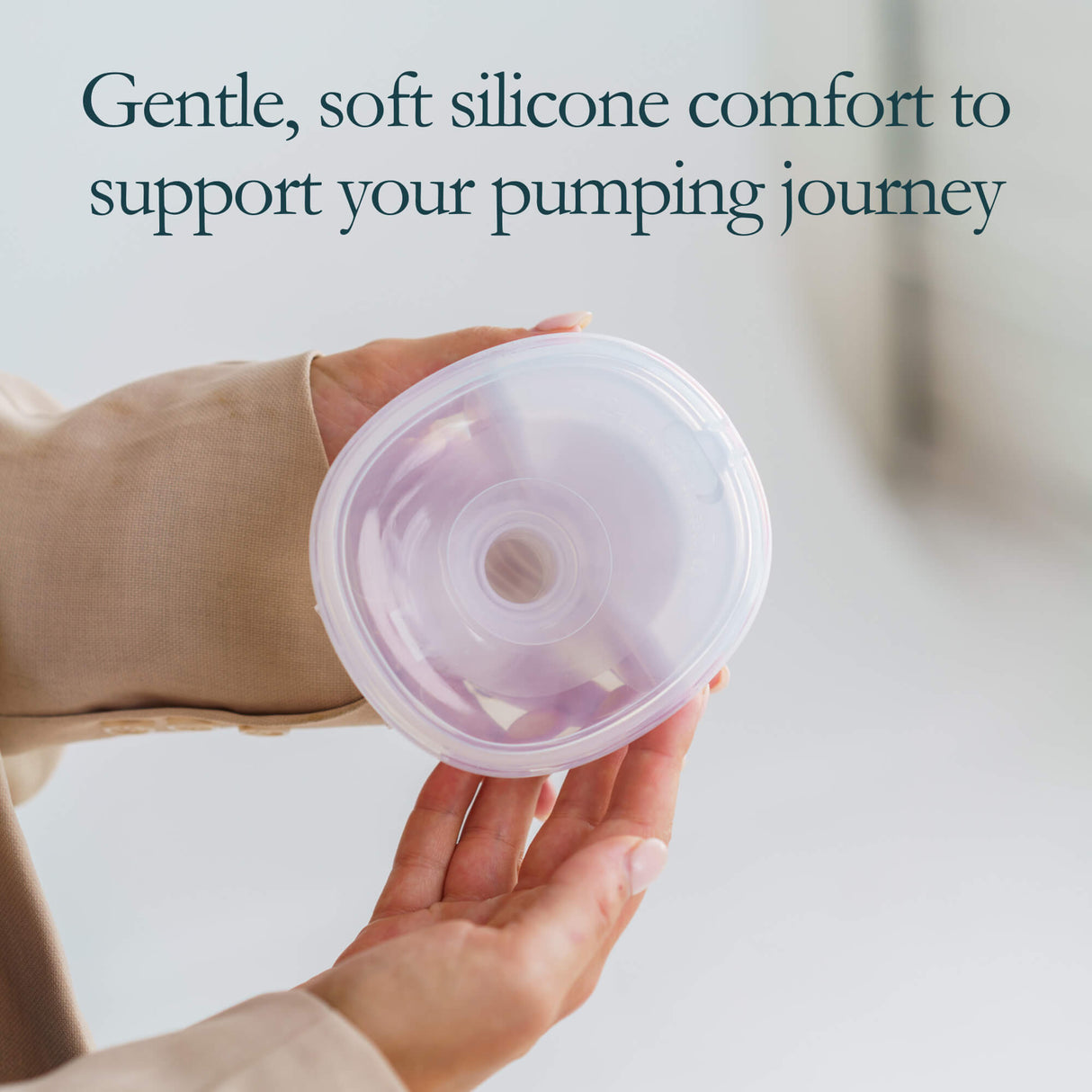 Hand holding a silicone breast pump cover with text reading "Gentle, soft silicone comfort to support your pumping journey".