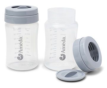 Two transparent plastic storage containers designed for breast milk, labeled with the brand name "Ameda" in a circular logo. One container is upright with a gray lid, while the other is slightly to the side with no lid. A gray screw-top lid is placed nearby, indicating that it can be used with the containers. The containers feature measurement markings on the sides to indicate volume.