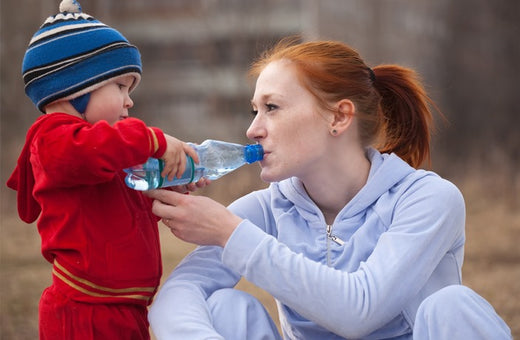 Baby holding a water bottle up to give their mother a drink