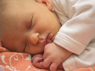 Newborn baby sleeping on a pink blanket