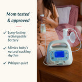 A breast pump machine sits on a wooden bedside table next to a woman in a bedroom, with text on the left reading 'Mom tested & approved' and feature bullet points about rechargeable battery, baby-like suckling rhythm, and whisper quiet.