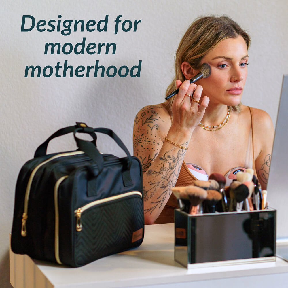 Woman applying makeup with a black bag labeled 'Designed for modern motherhood' in the foreground.
