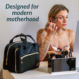 Woman applying makeup with a black bag labeled 'Designed for modern motherhood' in the foreground.